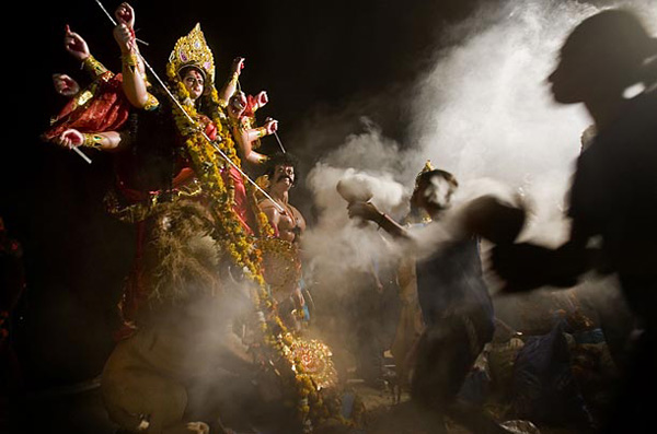 Молодые женщины танцуют перед идолом индусской богини Дерги