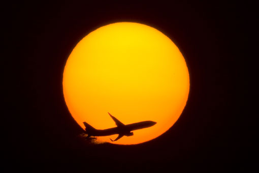 Пассажирский самолет на фоне солнца