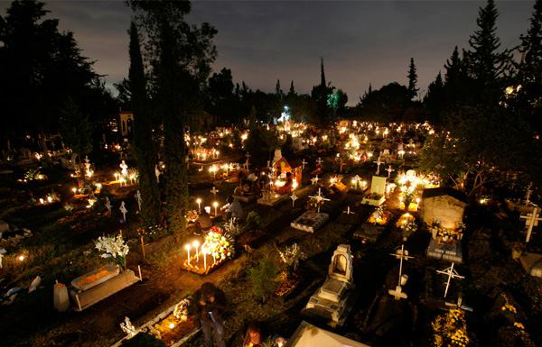 Свечи на могилах на кладбище Сан Грегорио во время празднования Дня Мертвых в Мехико