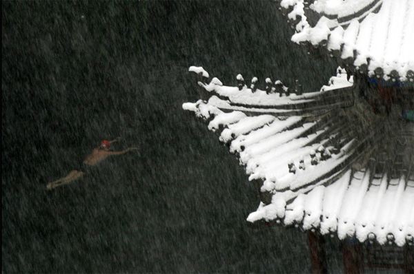 Человек плывет в озере невзирая на снегопад