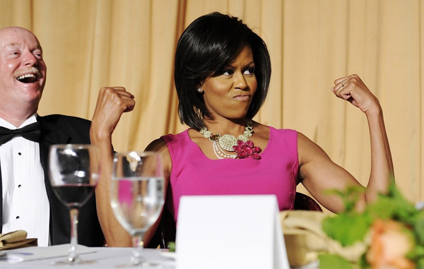 Первая леди США Мишель Обама играет мускулами в ответ на шутку о ее привычке носить платья без рукавов во время Обеда Ассоциации Корреспондентов Белого дома в Вашингтоне