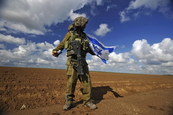 Израильский солдат держит национальный флаг после возвращения в Израиль из Сектора Газа 