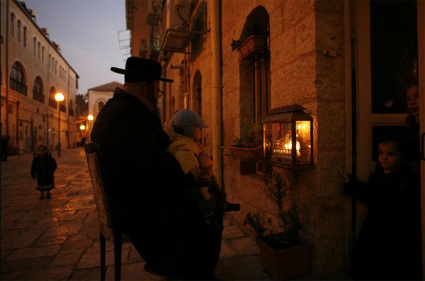 Ультраортодоксальная еврейская семья зажигает ханукальные свечи в Иерусалиме