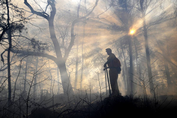 Пожарный в  Crowders Mountain State Park в Гастонии (Северная Каролина) смотрит за тем, чтобы пожар не распространялся