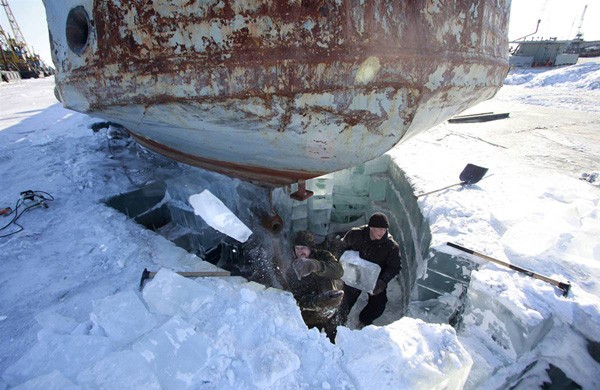 Рабочие убирают из-под судна ледяные блоки, чтобы освободить двигатель